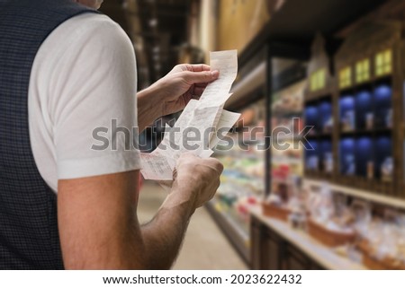 Closeup of young man holding bill to check the price in supermarket Foto stock © 