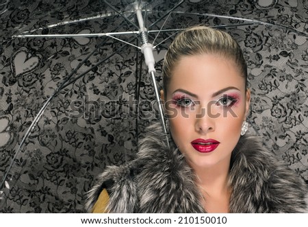 Beautiful young blonde woman wearing a fur and holding an umbrella. umbrella is a background