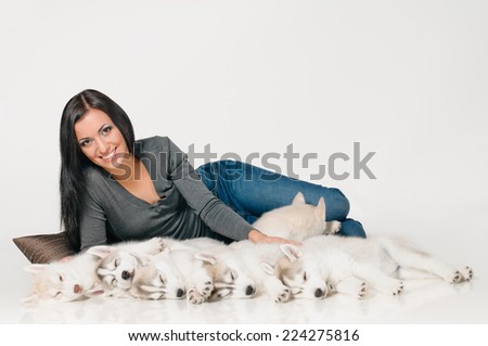 playing woman with puppies of siberian haski on grey background