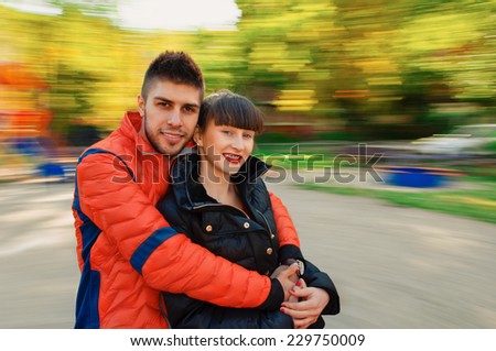 couple having fun on spinning roundabout. Autumn. Naturally blur motion