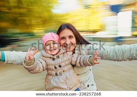 mother with her children having fun on spinning roundabout. Autumn. Naturally blur motion