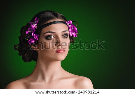 Beauty portrait of young woman with purple floral wreath over dark green background
