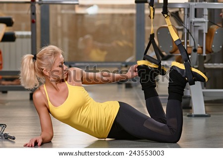 Young woman doing push-ups while legs hanging on elastic rope