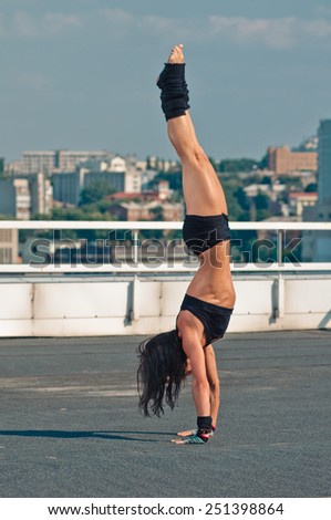 Handstand yoga pose by woman on the house-top