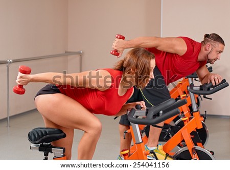 Happy couple doing indoor biking in a fitness club