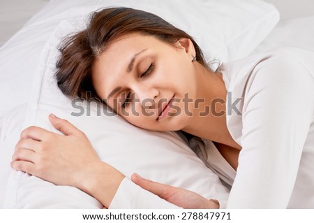 Young beautiful happy woman sleeps on bed, close up