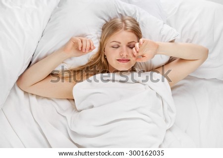 Young beautiful happy woman sleeping on bed, shot from above