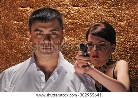 An attractive young couple with gun about wall