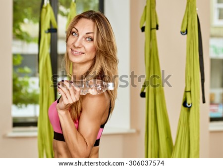Young woman posing about anti-gravity aerial yoga green hammock indoor with bottle water