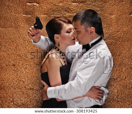 An attractive young couple with gun about wall