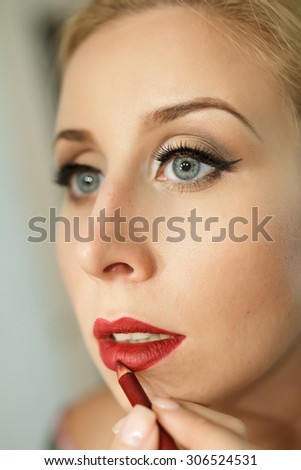 Makeup artist woman paints her lips with a pencil. Closeup portrait.