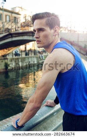 Tired athletic man resting after work out  by the river
