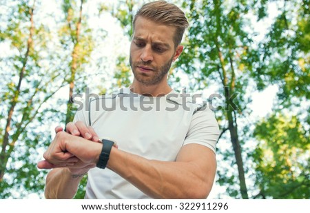 Young handsome athletic man checking his pulse after work out