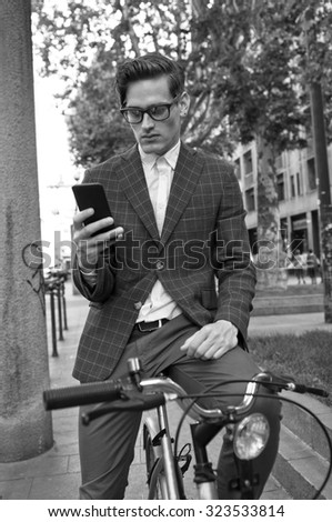 Black and white picture of a young handsome office worker going to work on his bicycle. Healthy lifestyle concept.