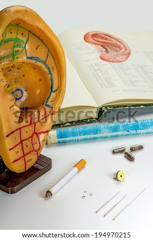 Acupuncture needles, ear model, textbook, moxa cone and herbal pills
