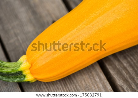 Yellow zucchini on the wooden floor, close-up