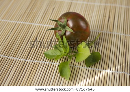 Black tomatoes and basil on mat