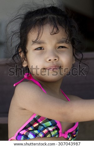 Thailand little girl with tanning skin and curly hair, Squint because the light reflected from the beach.
