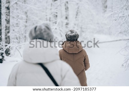 Photo of Winter snow walk woman walking away in snowy forest on woods trail outdoor lifestyle active people. Outside leisure.