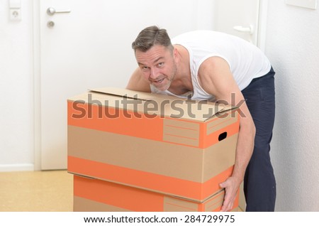 Happy friendly middle-aged man moving home carrying two cardboard cartons packed with his personal belongings