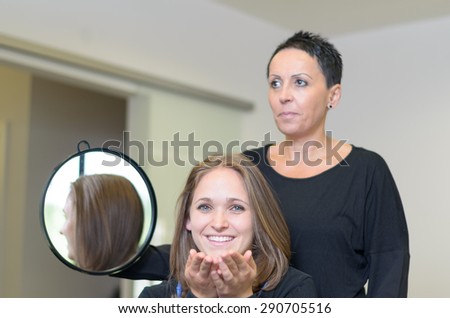 Happy Female Customer In a Salon Sitting In Front a Hairdresser Woman Holding a Round Mirror, Smiling at the Camera After Styling her Hair.
