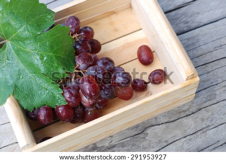 Red grape in wood box on wooden background