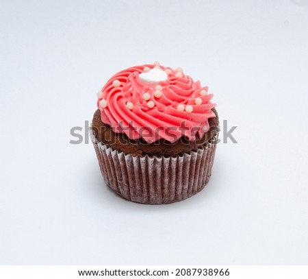 Chocolate cupcake decorated with red pink icing and sprinkles isolated on white
