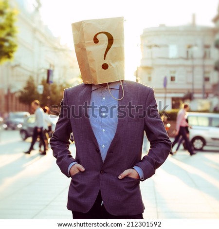 Businessman with a paper bag on head in the street