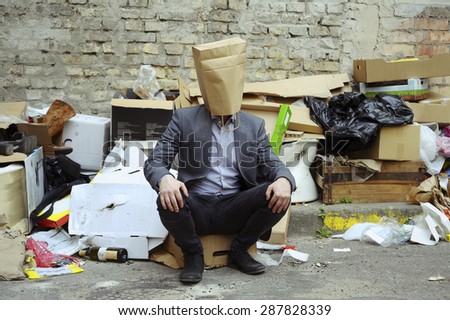 Man with paper bag on the head in the rubbish