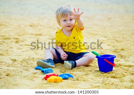 Cute little boy playing with his toys in the sandpit