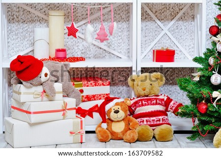 Closeup of cozy interior Christmas decoration with pine tree, gift boxes, candles and teddy bears