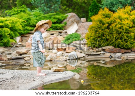 Cute child fishing by the pond in the beautiful garden