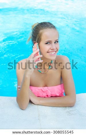 Summer holidays, leisure time. Beautiful young woman talking on the mobile phone in the swimming pool