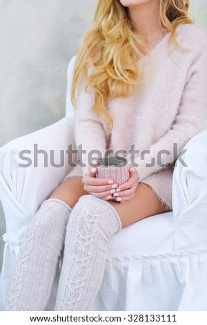 Woman hands holding cup; cozy knitted sweater, knee socks and cup decoration