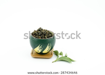 Dry Chinese oolong green tea in green japanese cup with white background
