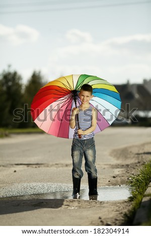 little happy boy with a rainbow umbrella in park