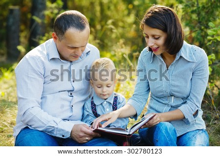 Happy family reading book in summer park