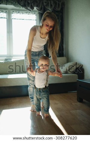 young beautiful mother teaches baby to walk