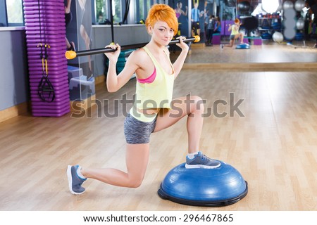 Redhead girl with short haircut and nice body is crouching in the gym