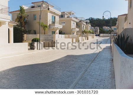 Clean light street with pavement trees and the same neat white houses covered with red tile, Protaras in Cyprus