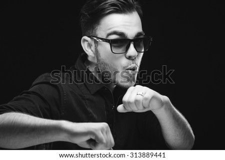 Cheerful bearded man wearing in black shirt and sunglasses. Studio shot on black background, close up