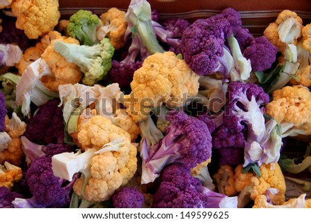 Bunches of fresh yellow, white, purple and green cauliflower heads at the farmers market