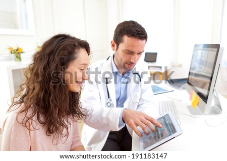 View of a Doctor using tablet to inform patient