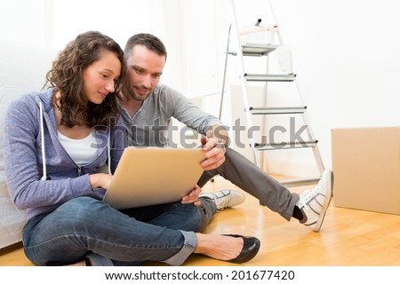View of a Young couple using laptop while moving in new flat