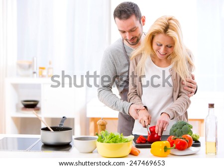 View of a Young attractive man helping out his wife while cooking