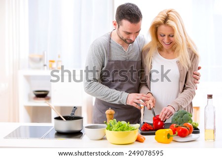 View of a Young attractive man helping out his wife while cooking