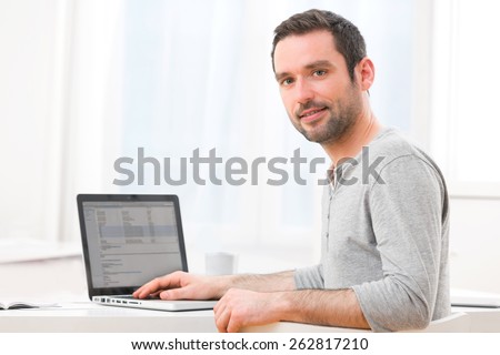 View of a Young smiling man in front of a computer