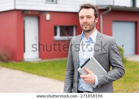 View of a young real estate agent in front of a house