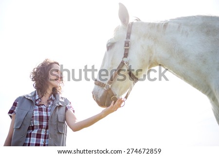 View of a young attractive veterinary in fields with horse