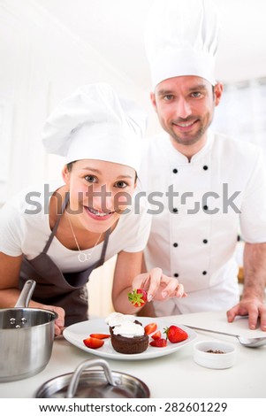 View of a Young chef training a young attractive girl to cook